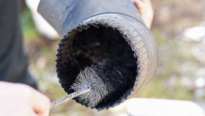 a chimney sweep cleaning out a piece of pipe